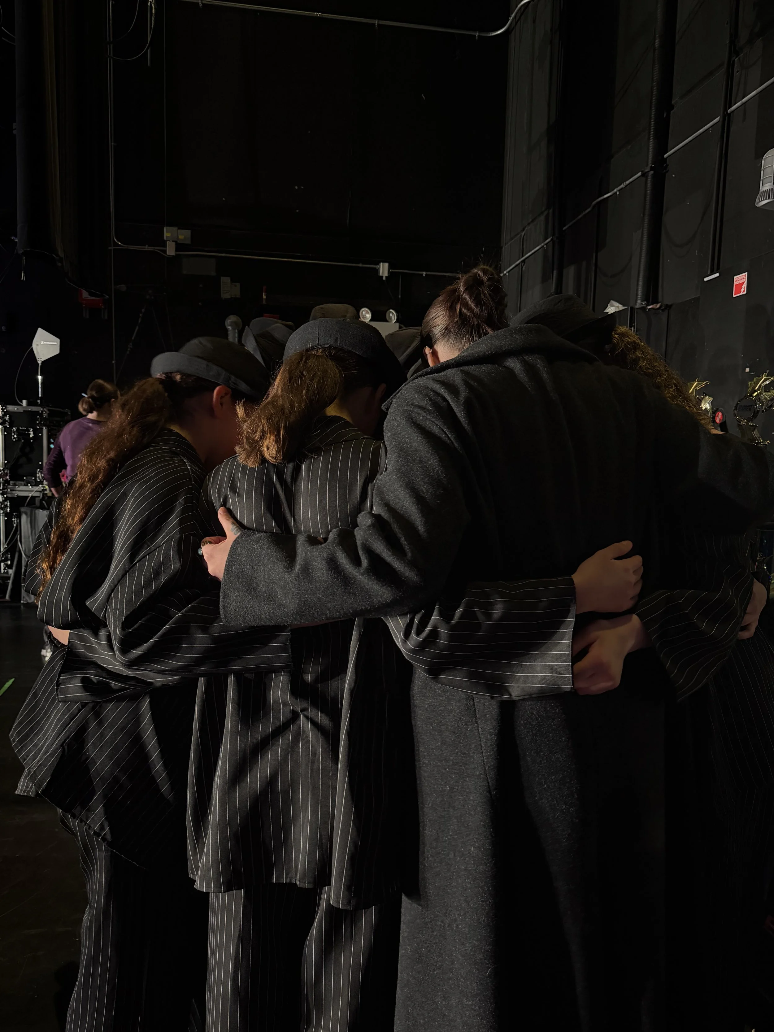 A group of young dancers and their teacher hugging in a circle